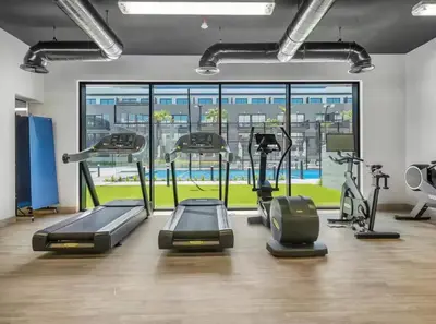 a gym with several treadmills and elliptical machines at Luxury Apartment in Oakley Square Residences, JVC in Dubai