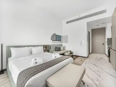 a white bedroom with a large bed and a living room at Sukoon's Elegant Suite 2 in Dubai