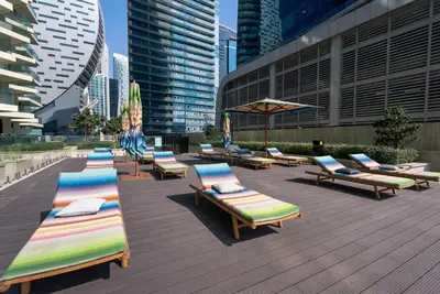 a row of chaise lounges and umbrellas on a deck at Luxury 1 & 2 BHK Apartments, Branded & State of The Art Amenities in Dubai