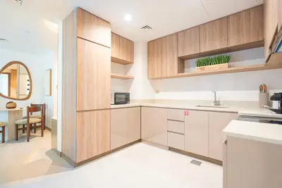 a kitchen with white counters and wooden cabinets at Luxury 1 & 2 BHK Apartments, Branded & State of The Art Amenities in Dubai