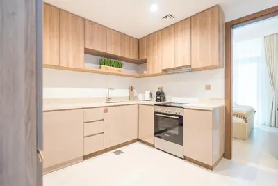 a kitchen with wooden cabinets and a stove at Luxury 1 & 2 BHK Apartments, Branded & State of The Art Amenities in Dubai