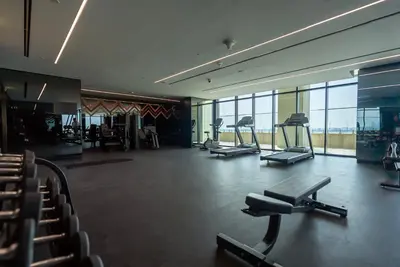 a gym with several treadmills and chairs in a building at Luxury 1 & 2 BHK Apartments, Branded & State of The Art Amenities in Dubai