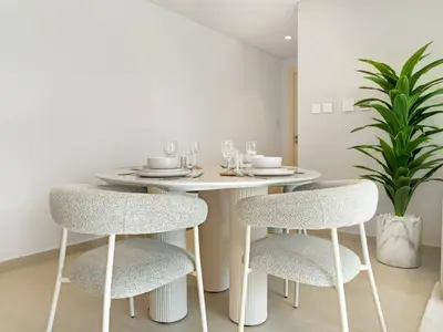 a white dining room table with two chairs and a plant at 2BR near Dubai Mall, Burj views! in Dubai