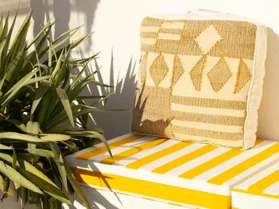 a pillow on a striped bench next to some plants at Unique Beachside Studio, Shared Pool & Burj Khalifa View! in Dubai