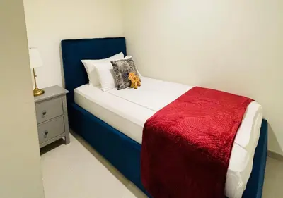 a bedroom with a blue and white bed with a red blanket at Direct Burj Khalifa View I Minutes Walk to Dubai Mall I Stunning Fountain Views I One Lux Stay Grande Signature Residence in Dubai