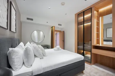 a bedroom with a bed with white pillows and a mirror at StayShort - Luxurious 2-Bedroom Apartment perfect for families in Dubai Marina in Dubai
