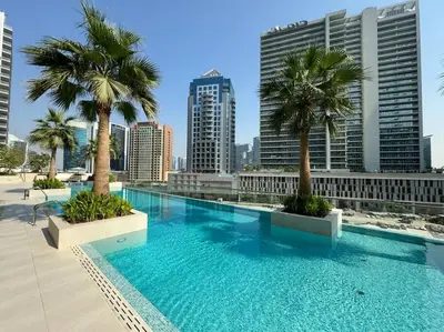 a large swimming pool with palm trees in a city at Luxury Living Studio in the Heart of Business Bay in Dubai