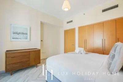 a bedroom with a large bed and a wooden dresser at LUX The Shemara Marina View Suite in Dubai