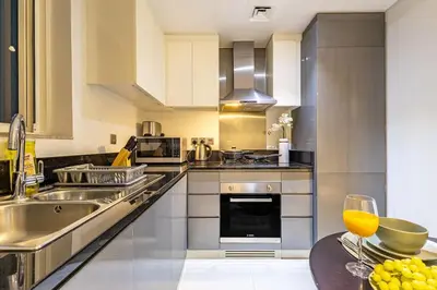a kitchen with stainless steel appliances and a table at Spacious Studio with Pool - Canal & Burj Views in Dubai
