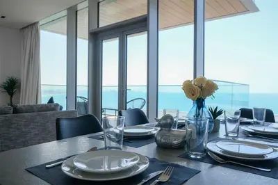 a dining room with a table with a view of the ocean at Mira Holiday Homes - Luxury 1 bedroom with sea view in Dubai