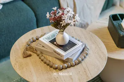 a table with a vase sitting on top of a book at 1BR Apt Near Downtown Dubai with Pool & Skyline Views in Dubai