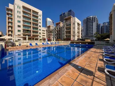 a large swimming pool with lounge chairs and buildings at Frank Porter - Al Samar 1 in Dubai