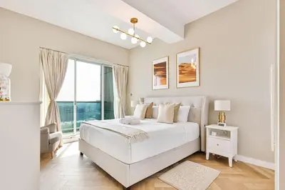 a white bedroom with a large bed and a window at Urban Oasis 1BR in Armada with Cityscape Views in Dubai