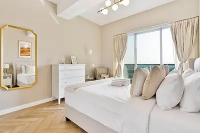 a white bedroom with a large bed and a mirror at Urban Oasis 1BR in Armada with Cityscape Views in Dubai