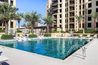 a swimming pool in a hotel with chairs and palm trees at Asayel Apartments in Dubai