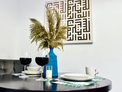 a table with wine glasses and a blue vase with a plant at Top Floor Luxurious Apt in JVC, Near Marina in Dubai