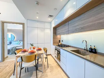 a kitchen with white cabinets and a table with chairs at Super Luxury Flat Desing with Sea, Marina and Pool View in Dubai