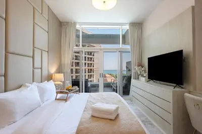 a large white bedroom with a large bed and a television at Livbnb-Premium 1B with BurjAlArab Views in Mina in Dubai