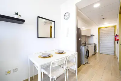 a kitchen with a white table and chairs in a room at Lovely Studio in Bloom Tower, 10 minutes to Marina in Dubai