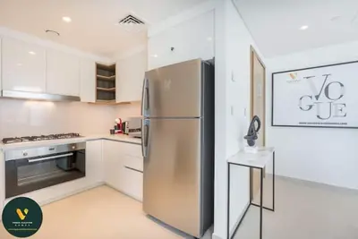 a kitchen with a stainless steel refrigerator and a stove at Vogue Downtown Views II with Direct Access to Dubai Mall Via a Climate Controlled Bridge, Three Bedroom Apartment plus kids room and Balcony with Burj Khalifa View in Dubai