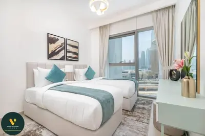 a white bedroom with two beds and a large window at Vogue Downtown Views II with Direct Access to Dubai Mall Via a Climate Controlled Bridge, Three Bedroom Apartment plus kids room and Balcony with Burj Khalifa View in Dubai