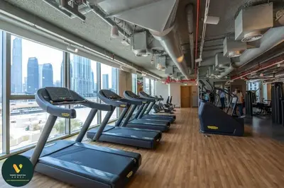 a gym with rows of treadmills in a building at Vogue Downtown Views II with Direct Access to Dubai Mall Via a Climate Controlled Bridge, Three Bedroom Apartment plus kids room and Balcony with Burj Khalifa View in Dubai