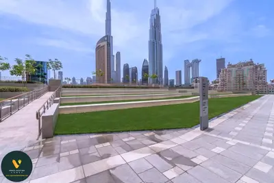a park with benches and grass in front of a city at Vogue Downtown Views II with Direct Access to Dubai Mall Via a Climate Controlled Bridge, Three Bedroom Apartment plus kids room and Balcony with Burj Khalifa View in Dubai
