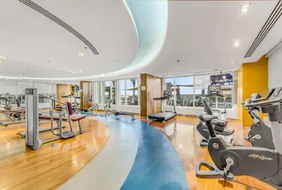 a gym with treadmills and elliptical machines at Waves - Stylish Studio with Balcony in Dubai South in Dubai