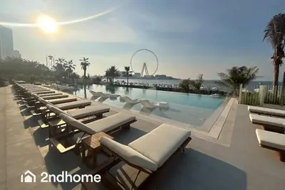a pool with chaise lounges and a roller coaster at La Vie, JBR - Your Perfect Holiday Gateway in Dubai