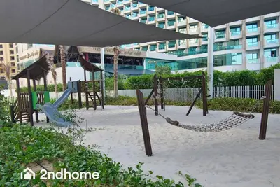 a playground in front of a large building at La Vie, JBR - Your Perfect Holiday Gateway in Dubai