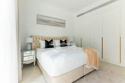 a white bedroom with a bed and a nightstand at La Vie, JBR - Your Perfect Holiday Gateway in Dubai