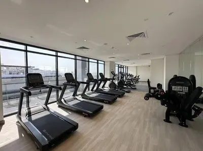 a gym with a row of treadmills and machines at Brand New Studio Near Downtown Dubai in Dubai