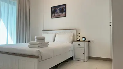 a white bedroom with a bed with towels on it at Sleek 1BR in DSO, Dubai in Dubai