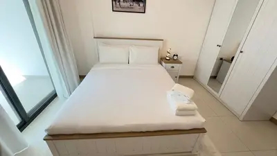 a white bed in a room with a large window at Sleek 1BR in DSO, Dubai in Dubai