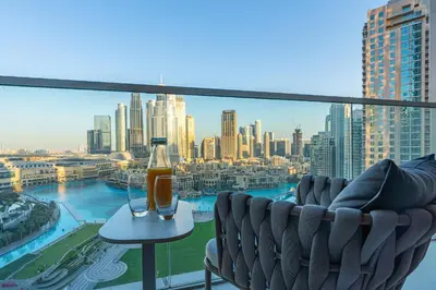 a balcony with a couch and a drink on a table at Skyline Majesty - Luxury Living with Full Burj Khalifa & Fountain Views in Dubai