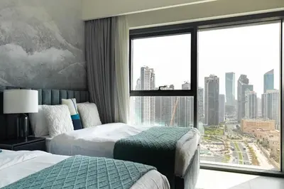 a hotel room with two beds and a large window at Arthouse Royale - 2BR with Burj Khalifa Views, Swimming Pool & Gym in Dubai