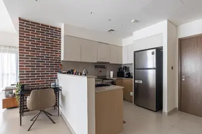 a kitchen with a refrigerator and a brick wall at Arthouse Royale - 2BR with Burj Khalifa Views, Swimming Pool & Gym in Dubai