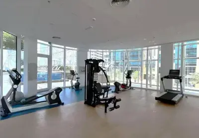 a gym with treadmills and ellipticals in a room with windows at DownTown, Amazing Business Bay Skyline Views in Dubai