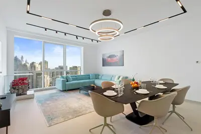 a living room with a table and a blue couch at Ferrari Inspired Modern 3BHK with maids room and Full Sea View in Dubai