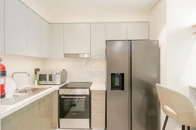 a kitchen with white cabinets and a stainless steel refrigerator at Forte Luxe - Stylish 2BR Downtown Escape in Dubai