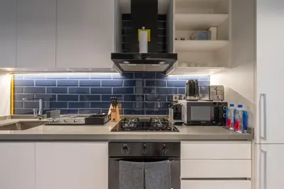 a kitchen with white cabinets and blue tile on the wall at Wohnung im Stadtzentrum von Dubai in Dubai