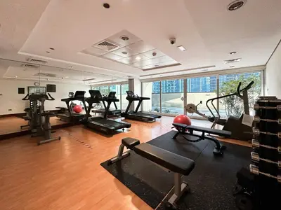 a gym with several treadmills and machines in a room at Trophy- Radiant Retreat in JLT With Skyline View in Dubai