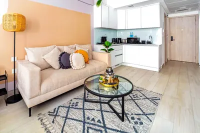 a living room with a couch and a glass table at Chic Modern Studio in Luma21, Best Pool & Gym in JVC Dubai in Dubai