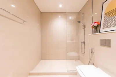 a white bathroom with a shower and a sink at Elegant 2BR in Burj Royale in Dubai
