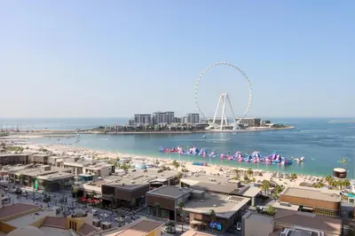 a view of a beach with a ferris wheel in the background at Upgraded 1B with Beach Access and Ain Dubai Views in Dubai