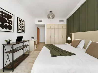 a bedroom with a bed and a desk with a laptop at Spacious Home in the heart of Marina w Seaview in Dubai