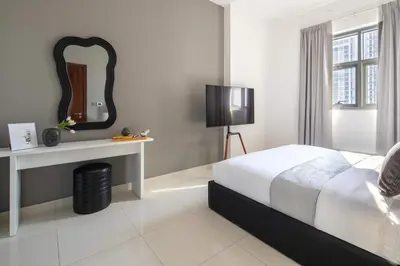 a white bedroom with a bed and a mirror at Frank Porter - Dezire Residences in Dubai
