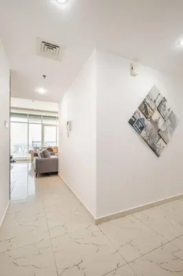 a living room with a white wall and a couch at Elegant 2BR Apartment in the Heart of Marina in Dubai