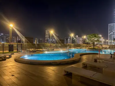 a swimming pool with a city skyline at night at Bright JVC Studio - Serenity Escape in Dubai