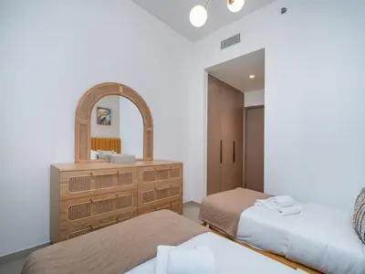 a bedroom with two beds and a dresser with a mirror at Luxury Downtown 3 Bed with Full Burj Khalifa Views in Dubai